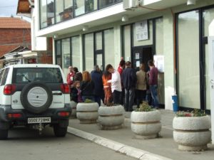 Voters queueing in front of a polling station and an OSCE vehicle